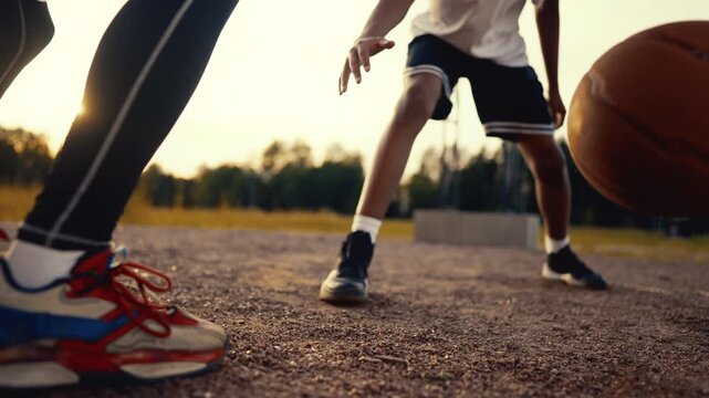 Cinematic handheld shot with two teens playing basketball on street, feet view. Sport and hobby for young people, do physical exercise and fitness for stay healthy and developing body conditions