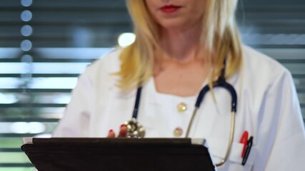 Close-up of a Caucasian female doctor using a tablet to examine patient digital medical records - Powered by Adobe