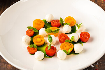 Colorful Caprese salad with cherry tomatoes, mozzarella and fresh basil