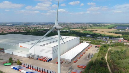 Aerial drone view of wind turbine, windmill, renewable energy generation electricity generation business district and warehouses distribution centres in Clumber Nottingham England UK