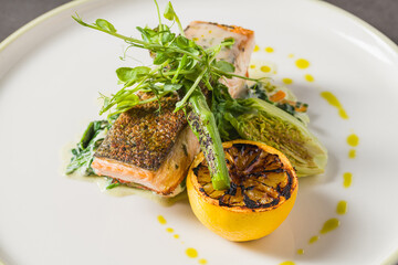 Grilled salmon fillet with charred lemon and greens on plate
