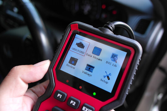 OBD2 scanner in hand, car diagnostic tool and code reader to check engine light, read and clear DTCs, view live data and voltage, automotive repair and maintenance