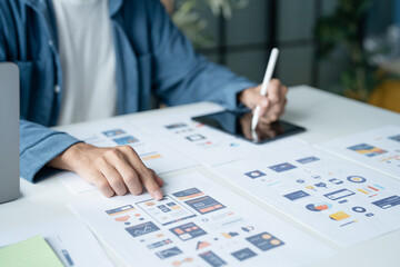 UX UI Designer Planning innovative Mobile App with Paper Wireframe Designs at Workspace.