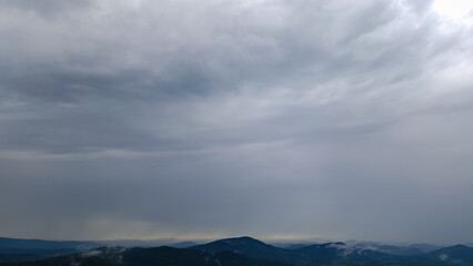 Obraz premium A sweeping view of green hills and distant mountains under a stormy sky, perfect for travel ads, nature documentaries, and eco-conscious branding