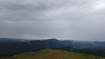 A sweeping view of green hills and distant mountains under a stormy sky, perfect for travel ads, nature documentaries, and eco-conscious branding