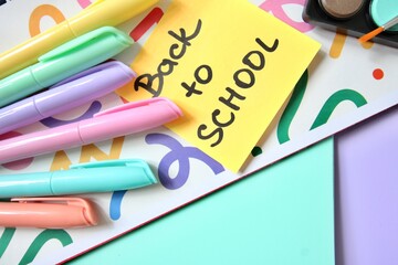 Flat lay composition of colorful school and art supplies arranged around a small easel with a blank canvas, set on pastel-colored paper background. Ideal for themes of back to school, creative