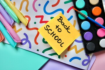 Flat lay composition of colorful school and art supplies arranged around a small easel with a blank canvas, set on pastel-colored paper background. Ideal for themes of back to school, creative