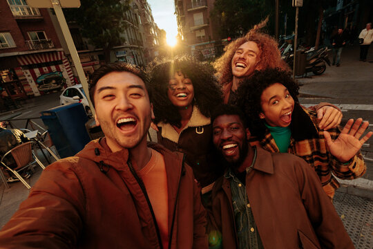 Group of cheerful multiracial friends taking photo of themselves in Madrid