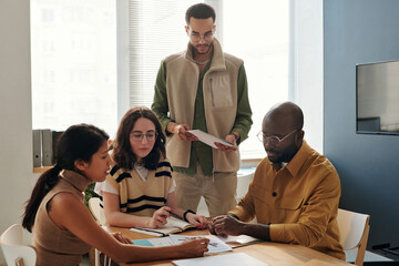 Team of colleagues cooperating at table during meeting, they discussing business marketing at office