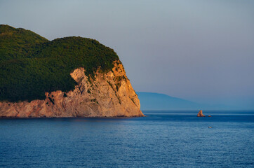 beautiful seascape, view of the sea and high cliff in the distance in the evening, near Petrovac city, Montenegro