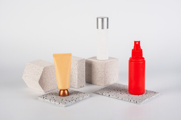 Plastic white tube for cream or lotion. Skin care or sunscreen cosmetic, Cosmetic red bottle. Womens cosmetic accessory for makeup with stylish props on white background.