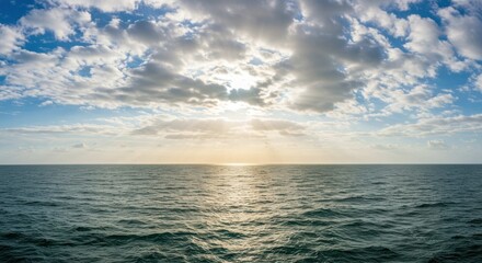 Obraz premium Ocean view with sun shining through clouds creating sunbeams over the water.