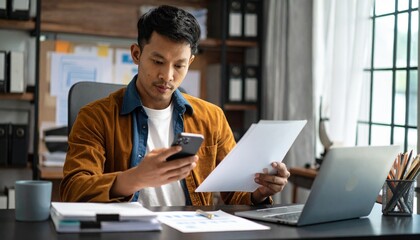 Obraz premium A person flipping through documents on a desk and checking their smartphone