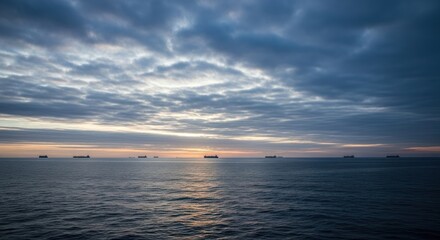 Obraz premium Calm ocean at sunrise, silhouette ships, dramatic sky