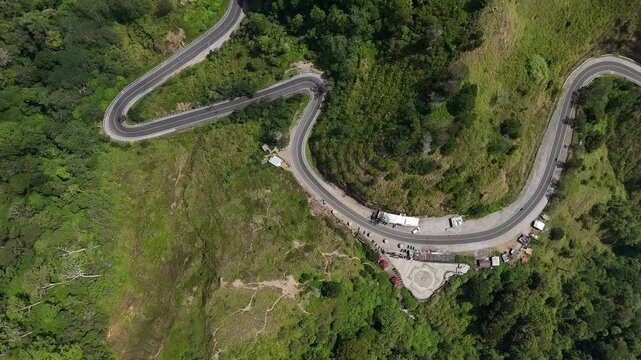 Overhead Drone View of Winding Mountain Road through Lush Tropical Forest with Cars and Scenic Overlook