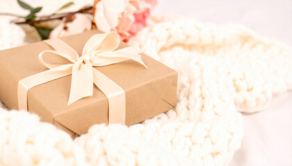 Wrapped Gift with Floral Elegance: a meticulously wrapped gift, adorned with a delicate satin ribbon, rests amidst a cascade of soft, inviting textures and floral details.