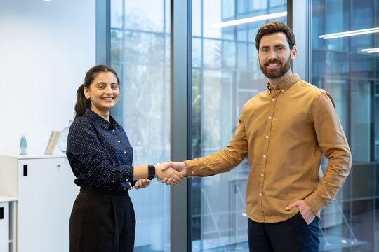 Two colleagues exchange a firm handshake, symbolizing trust and cooperation, in a professional and modern office environment setting, emphasizing teamwork, collaboration, and successful partnerships