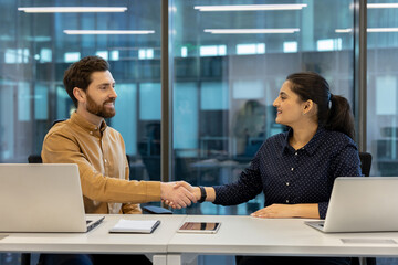 Two colleagues engage in a professional handshake, representing partnership and collaboration in business.
