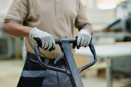 Medium section of unrecognizable African American print shop warehouse worker using pallet jack - Powered by Adobe