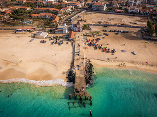 Aerial drone shot of the Santa Maria pier and beach, Sal Island, Cape Verde, at golden sunset. Turquoise waters, fishing boats and a tropical atmosphere in high resolution.