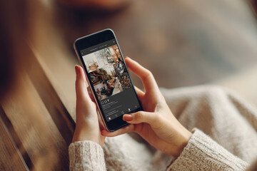 Woman scrolling through aesthetic social media feed on smartphone, finding inspiration for lifestyle.