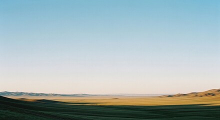 Vast and tranquil mongolian steppe landscape stretching endlessly under a clear blue sky.