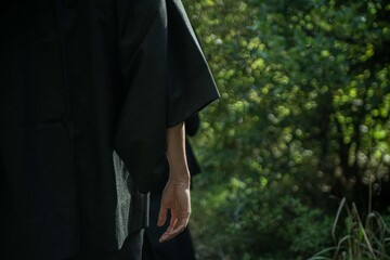 A samurai in black kimono is walking through forest.