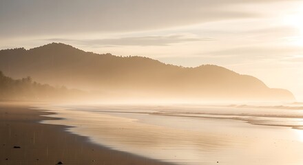 Golden light bathes the beach and mountains in a serene coastal landscape