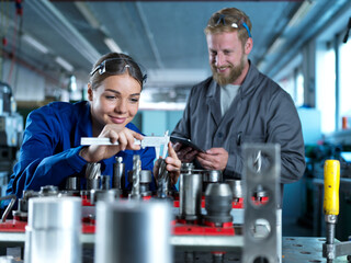 Smiling trainee learning to measure CNC tool at factory