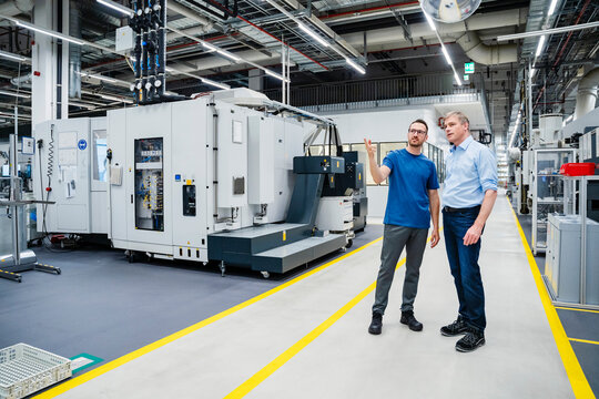 Employee talking to businessman in a factory