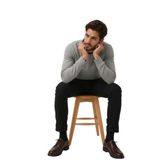 Handsome thoughtful man sitting on a stool wearing grey sweatshirt and black pants resting face looking away in contemplation and introspection style
