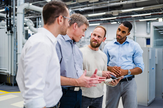 Businessman with digital tablet talking to colleagues in a factory