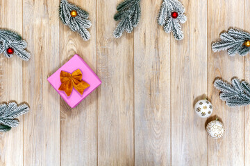 Snowy Christmas fir branches, sparkling ornaments, and festive gift on cozy rustic wooden table