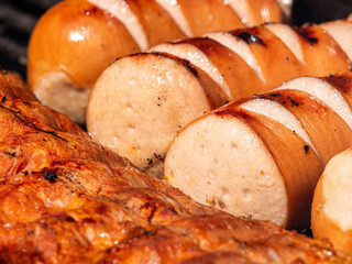 Well-seared and grilled spare ribs and meat sausage sizzling on a charcoal grill. Juicy meat with smoky aroma and golden crust, perfect for a summer barbecue feast.