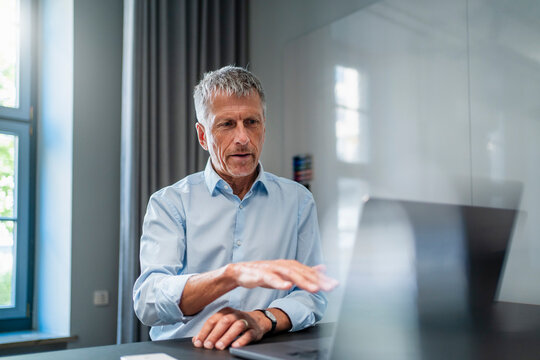 Senior businessman talking on video call through laptop at desk