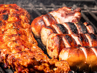 Well-seared and grilled spare ribs and meat sausage sizzling on a charcoal grill. Juicy meat with smoky aroma and golden crust, perfect for a summer barbecue feast.