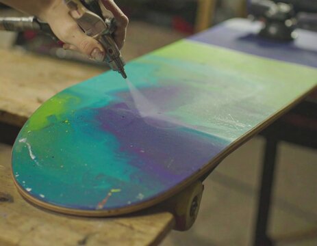Skateboard being spray painted - Powered by Adobe