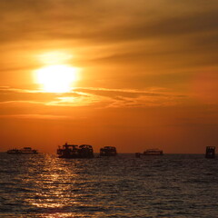 bright red sunset with shadows of boats in the water