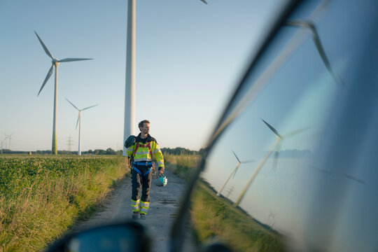 Technician on field path at a wind farm with climbing equipment