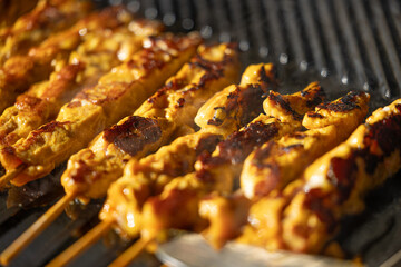 marinated chicken satay skewers grilling on hot barbecue with smoke rising, perfect for Asian street food, summer party and delicious grilled cuisine concepts.
