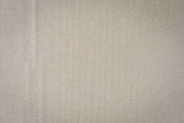 Close-up of textured beige corrugated cardboard surface, showcasing vertical ridges and subtle...