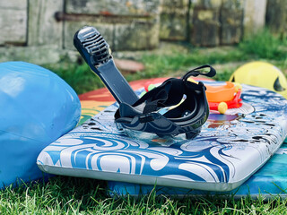 Snorkeling gear and bodyboard resting on grass in backyard setting.