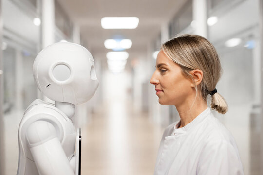 Woman researcher facing robot in modern medical laboratory