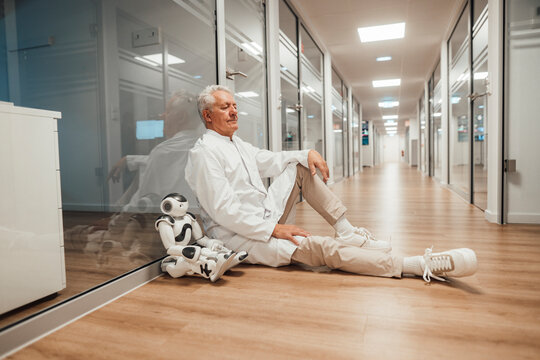 Scientist in white coat resting with robot in modern medical research facility