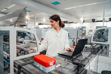 Scientist in modern laboratory analysing blood samples with laptop