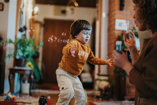 A delightful indoor scene capturing a cheerful child chasing soap bubbles as their mother blows them. The scene conveys joy, playfulness, and a warm family connection in a cozy home environment.