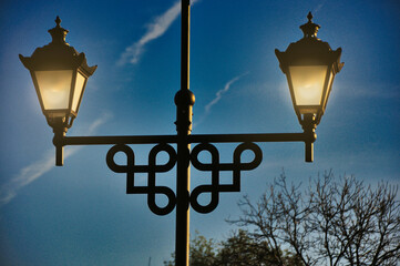 W centrum uwagi znajduje się lampa uliczna w stylu vintage - ponadczasowy miejski design - na tle spokojnego, wieczornego błękitnego nieba. © Pol Badger