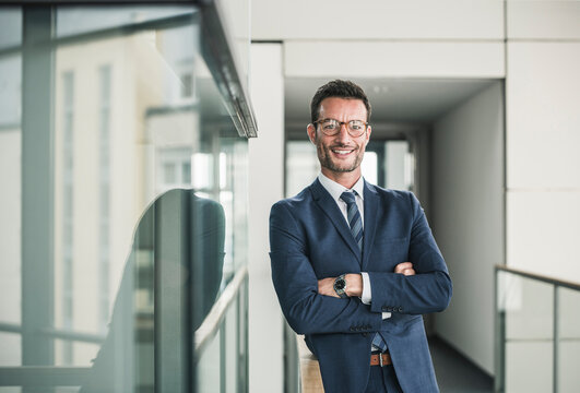 Portrait of a successful businessman, standing in office building, with arms crossed