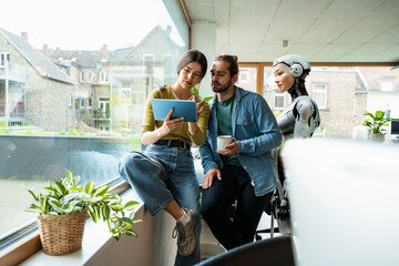Humanoid robot with business colleagues using tablet PC in office