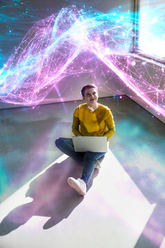 Woman sitting on floor with laptop and digital data stream